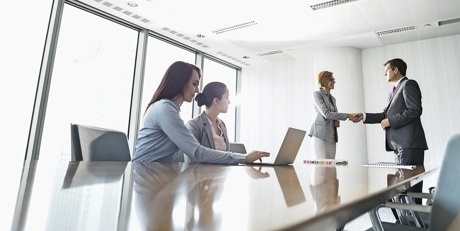 Businesspeople shaking hands in board room